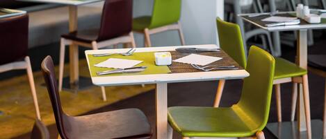 A modern dining area with wooden tables and green chairs.