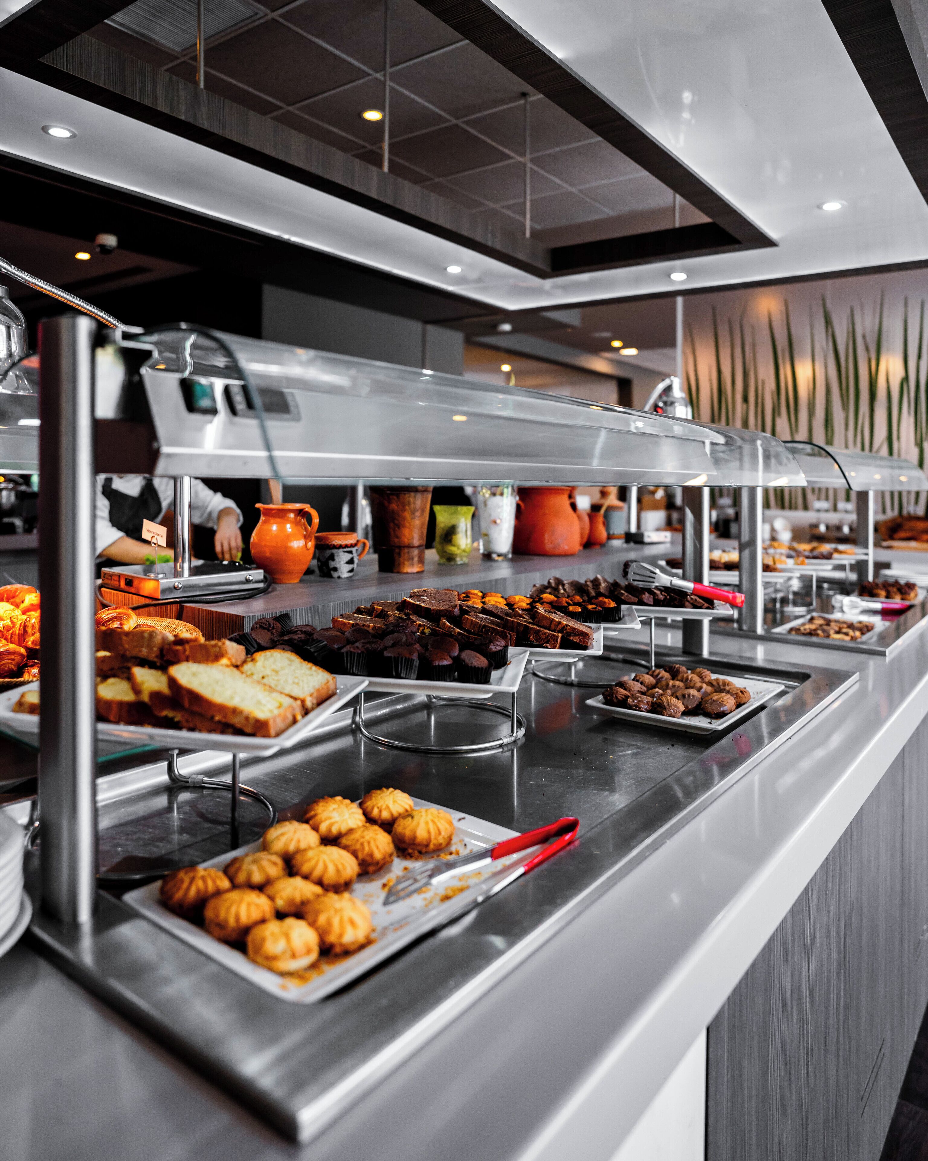 Ein Buffet mit verschiedenen Speisen, darunter Gebäck, Brot und Desserts.