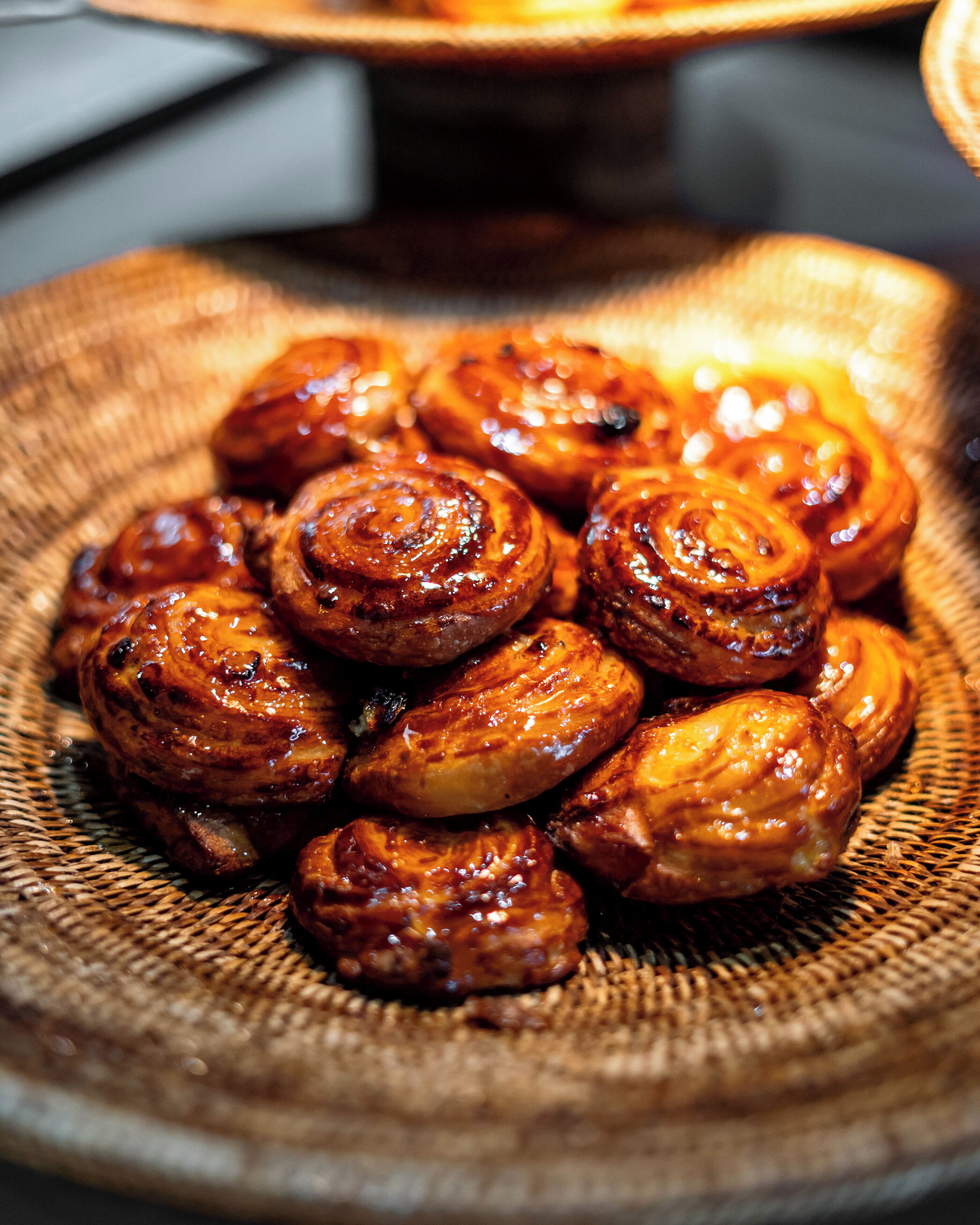 A close-up of glazed pastries on a woven plate.