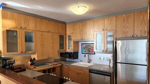 A modern kitchen with wooden cabinets, stainless steel appliances, and a central island. - Oceanfront Paradise Awaits at Kahana Reef 215 (Lahaina)