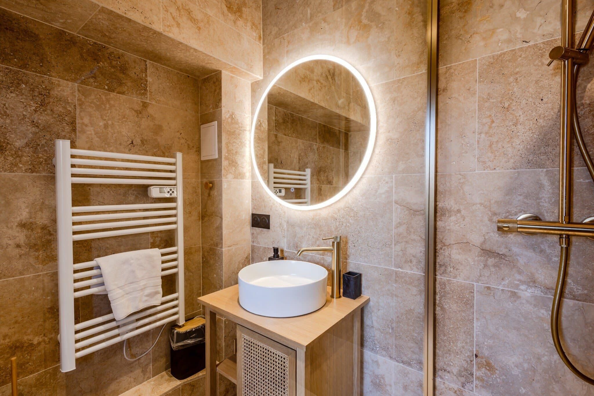 A modern bathroom with a round mirror, white sink, and a towel rack.