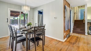 Un coin repas avec une table et des chaises en bois, un lustre et une vue sur le jardin.