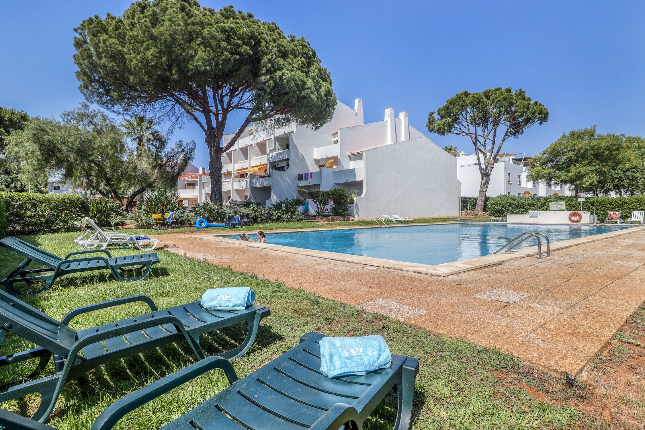A swimming pool area with lounge chairs and a building in the background.
