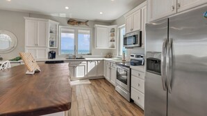 A modern kitchen with white cabinetry, stainless steel appliances, and a wooden countertop.