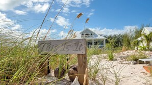 A beach house with a sign in the foreground.