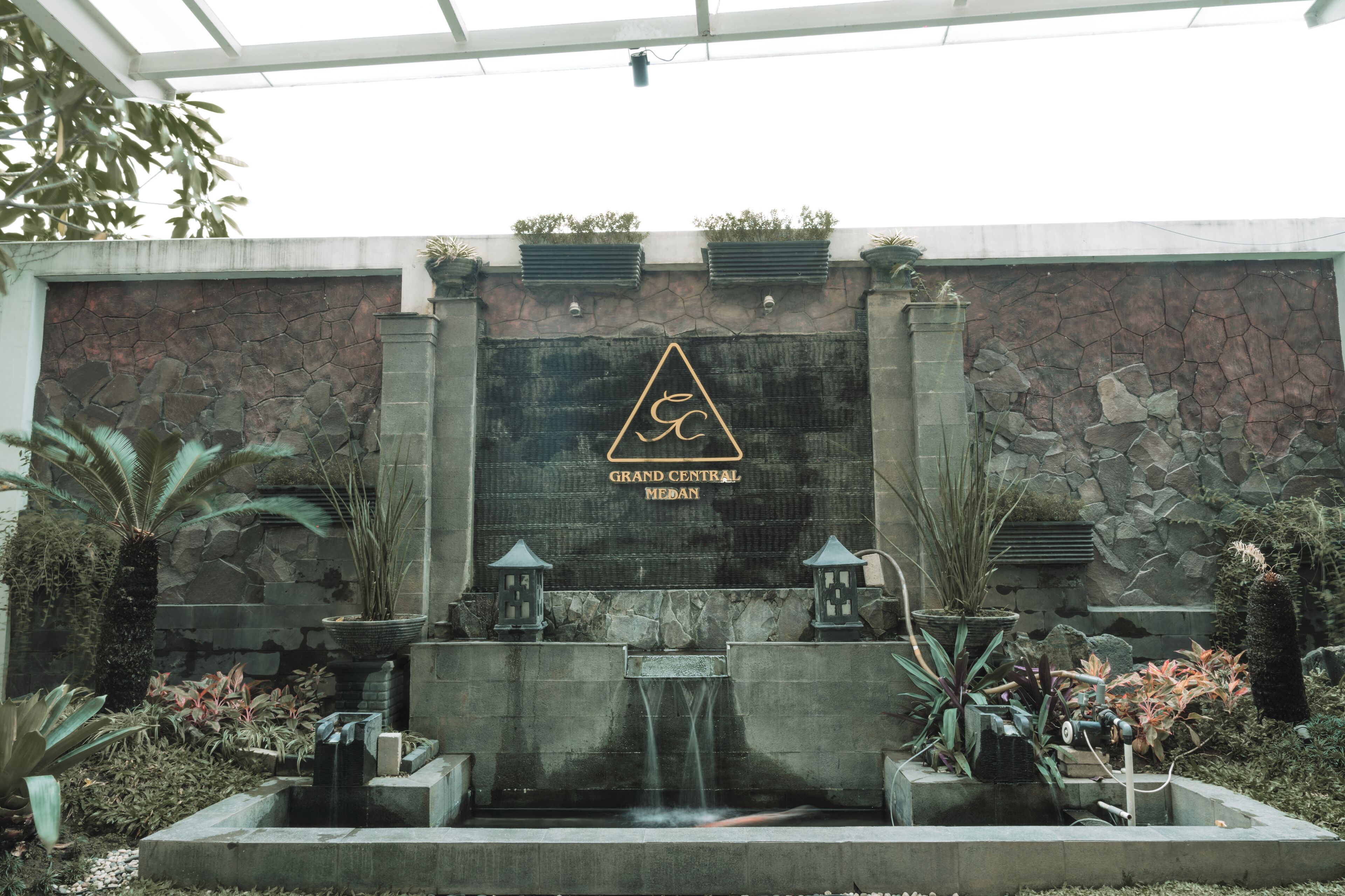 Een stenen muur met een waterval en plantenpotten.