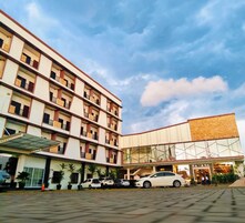 Un hotel de varios pisos con diseño moderno, que destaca por una fachada de vidrio y una zona de estacionamiento techada.