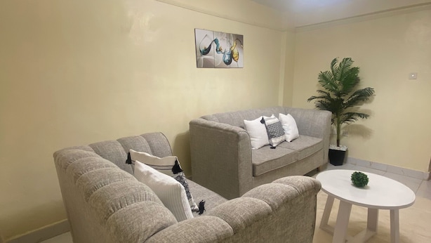 Ein Wohnzimmer mit Ecksofa, einem zusätzlichen Sofa, einem runden Couchtisch und einer Zimmerpflanze.