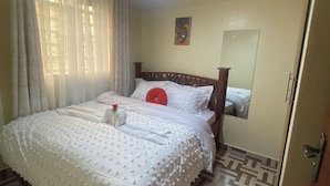Ein ordentlich eingerichtetes Schlafzimmer mit einem großen Bett, einem Spiegel und einem gemusterten Boden.