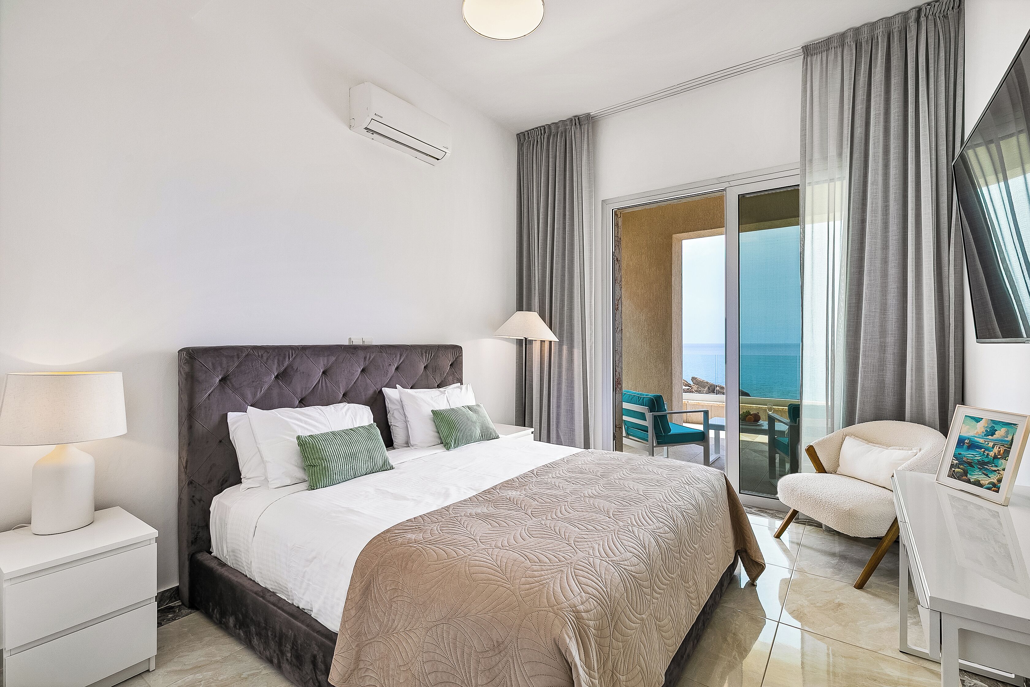 Camera d'albergo con un letto grande, un comodino, una scrivania, una sedia e vista sull'oceano dalla finestra.