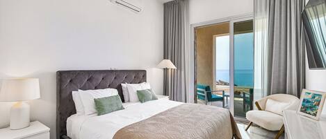 Camera d'albergo con un letto grande, un comodino, una scrivania, una sedia e vista sull'oceano dalla finestra.