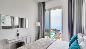 Une chambre d’hôtel avec un lit, un bureau, une chaise et une vue sur la mer.