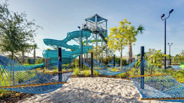 A sandy beach area with blue hammocks and a water slide structure.