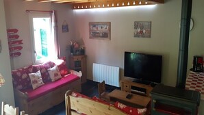 Un salon confortable avec un canapé, un téléviseur, une cheminée et un coin repas.