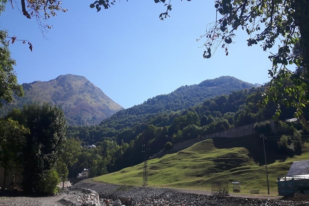 A mountainous landscape with a clear sky, a road, and a building on the left.