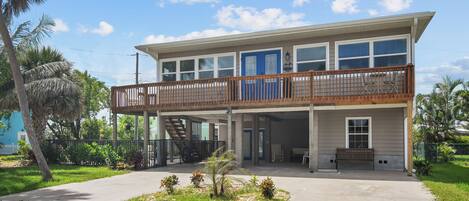 A two-story building with a balcony, a covered patio, and a staircase leading to an upper level.