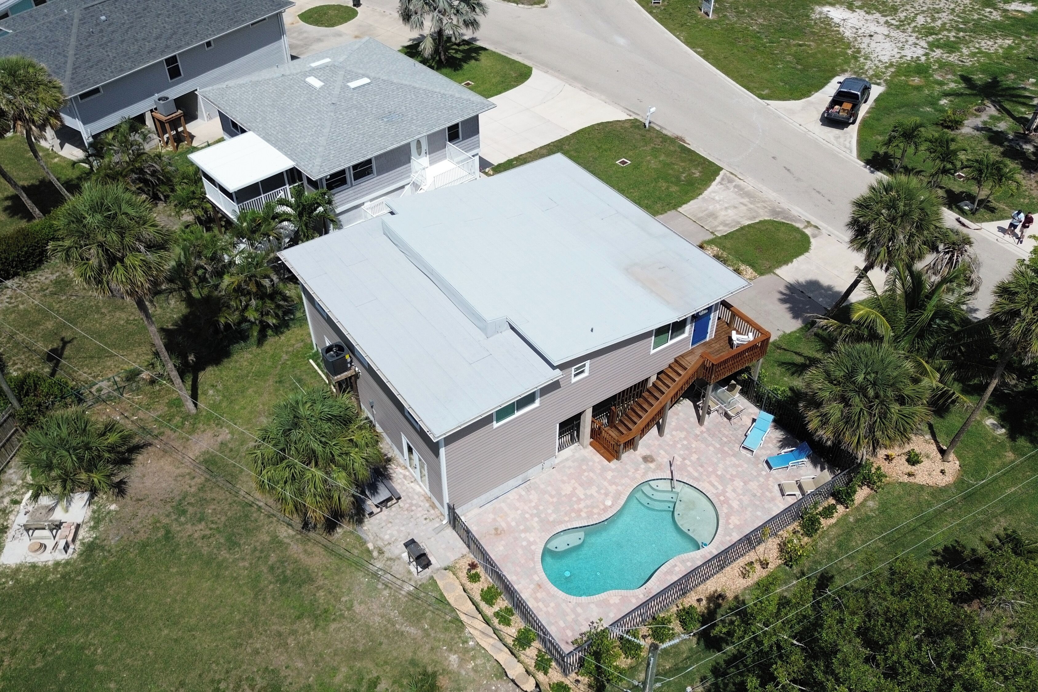An aerial view of a residential property with a swimming pool, a covered patio, and a detached garage.