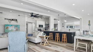 A modern kitchen with white cabinets, a black island, and wooden stools. - 1 Mi to Fort Myers Beach Access! Chic Coastal Home (Fort Myers Beach)