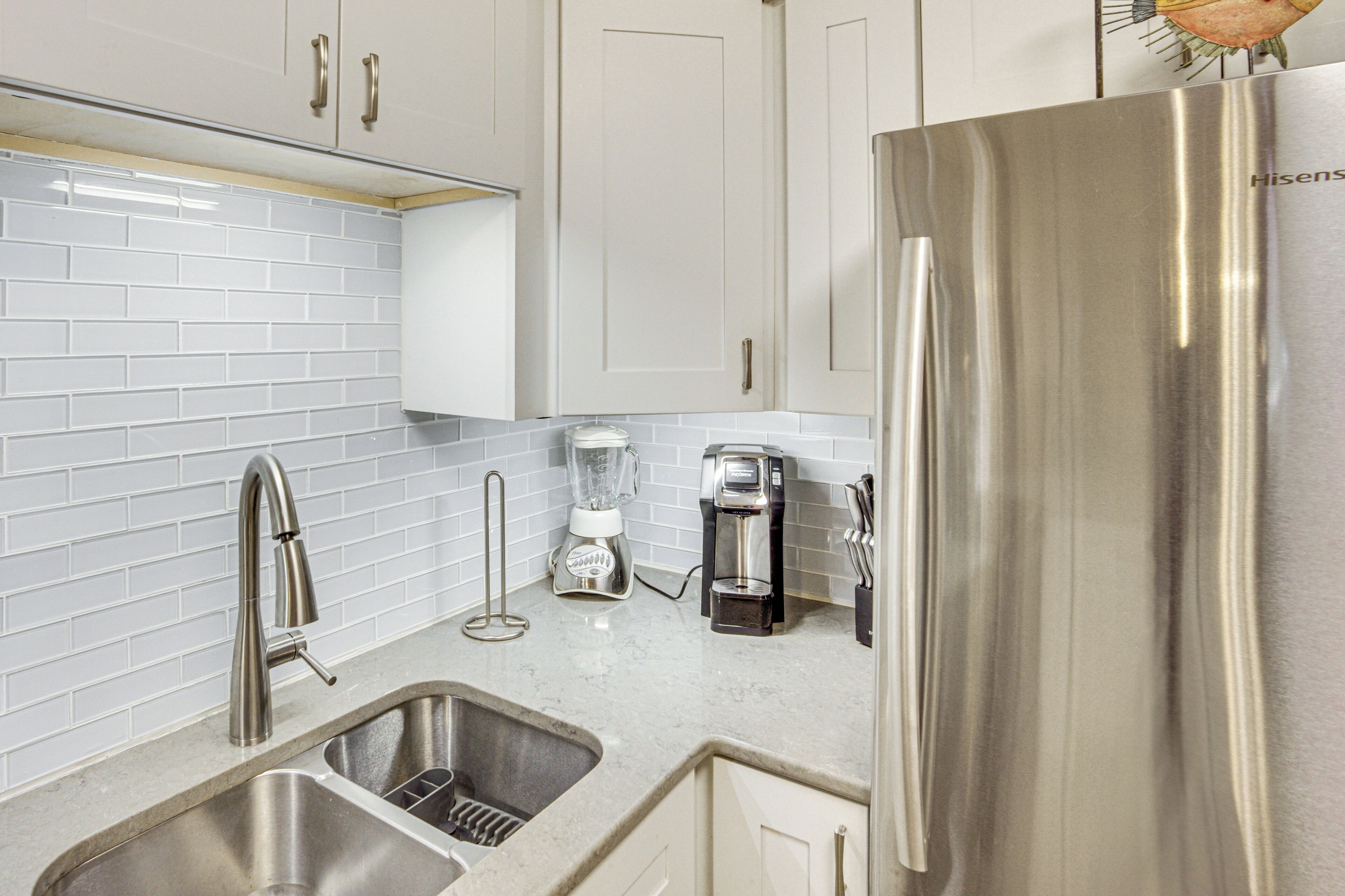 A kitchen with stainless steel appliances, a double sink, and white tiled backsplash.