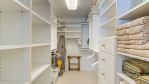 Ein übersichtlicher Kleiderschrank mit Regalen, einer Kleiderstange und einem kleinen Bügelbrett.