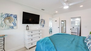 Ein Schlafzimmer mit Bett, Kommode, Fernseher und Bildern an den Wänden.