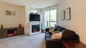 Una sala de estar con chimenea, un sofá y un televisor montado arriba.