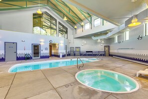 A multi-level indoor pool with clear water, a spa area, and a staircase connecting the levels.