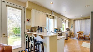 A kitchen with a large island, bar stools, a dining area with a table and chairs, and a view of the outdoors through the sliding glass door. - 1 Block to Bay: Pet-friendly Retreat in Alameda! (Alameda)