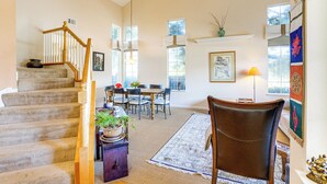 A spacious living area with a staircase, a dining table with chairs, a large rug, and a decorative chair. - 1 Block to Bay: Pet-friendly Retreat in Alameda! (Alameda)
