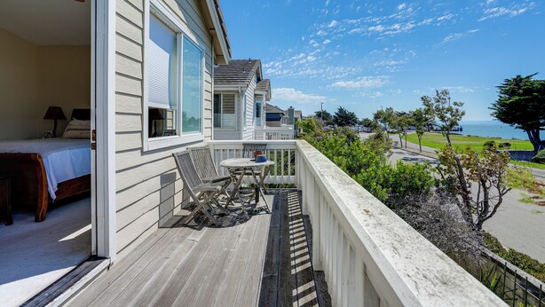 A balcony with a bed, a table, and chairs, overlooking a view of the ocean and a park. - 1 Block to Bay: Pet-friendly Retreat in Alameda! (Alameda)