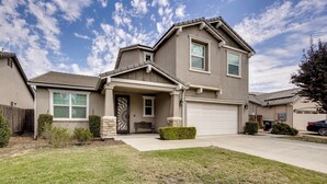 A two-story house with a front garage, a covered entryway, and a well-maintained lawn. - Group Getaway 5 Mi to Dtwn Visalia (Visalia)