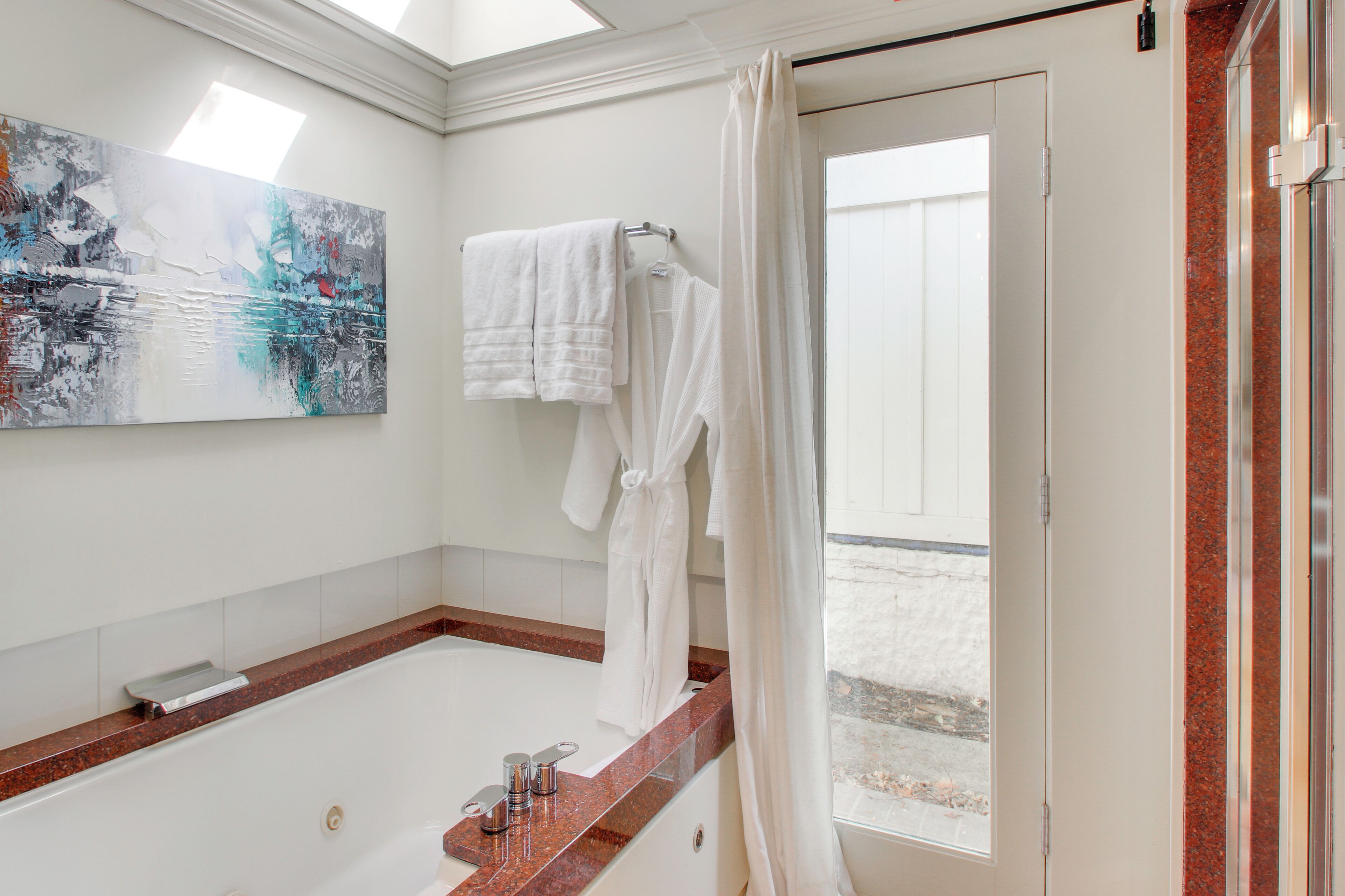 Un baño moderno con una bañera grande, cabina de ducha de vidrio y vistas al exterior.