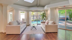 A modern hotel lobby with two sofas, a coffee table, and a large sliding glass door leading to a pool area. - 1 Mi to OU! Group Getaway w/ Game Room, Pool (Norman)