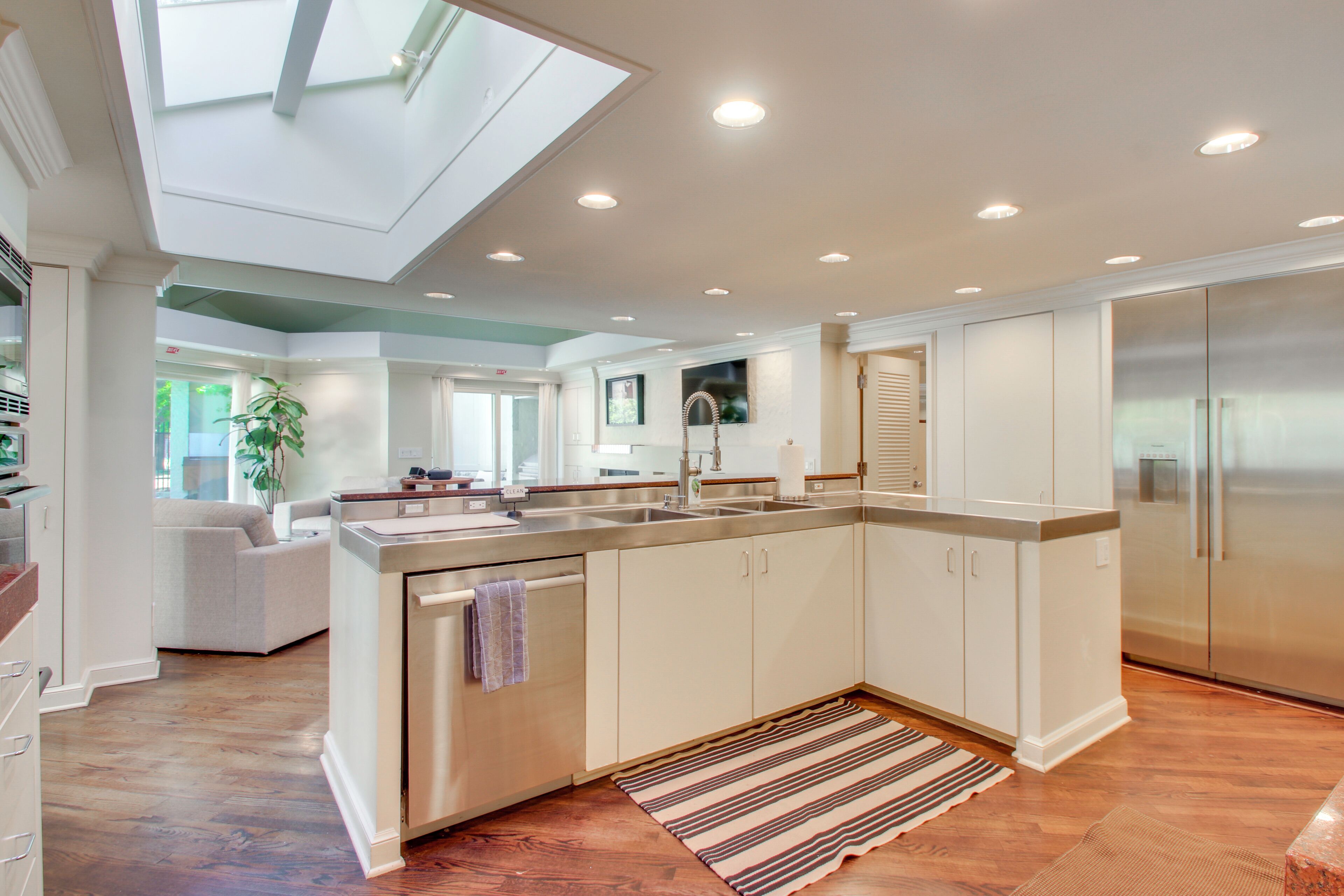 A modern kitchen with a central island, stainless steel appliances, and a skylight.