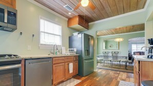 A modern kitchen with wooden cabinets, stainless steel appliances, and a dining area with a chandelier. - Historic Sunrise House w/ Game Room: Near Beach! (Fort Pierce)