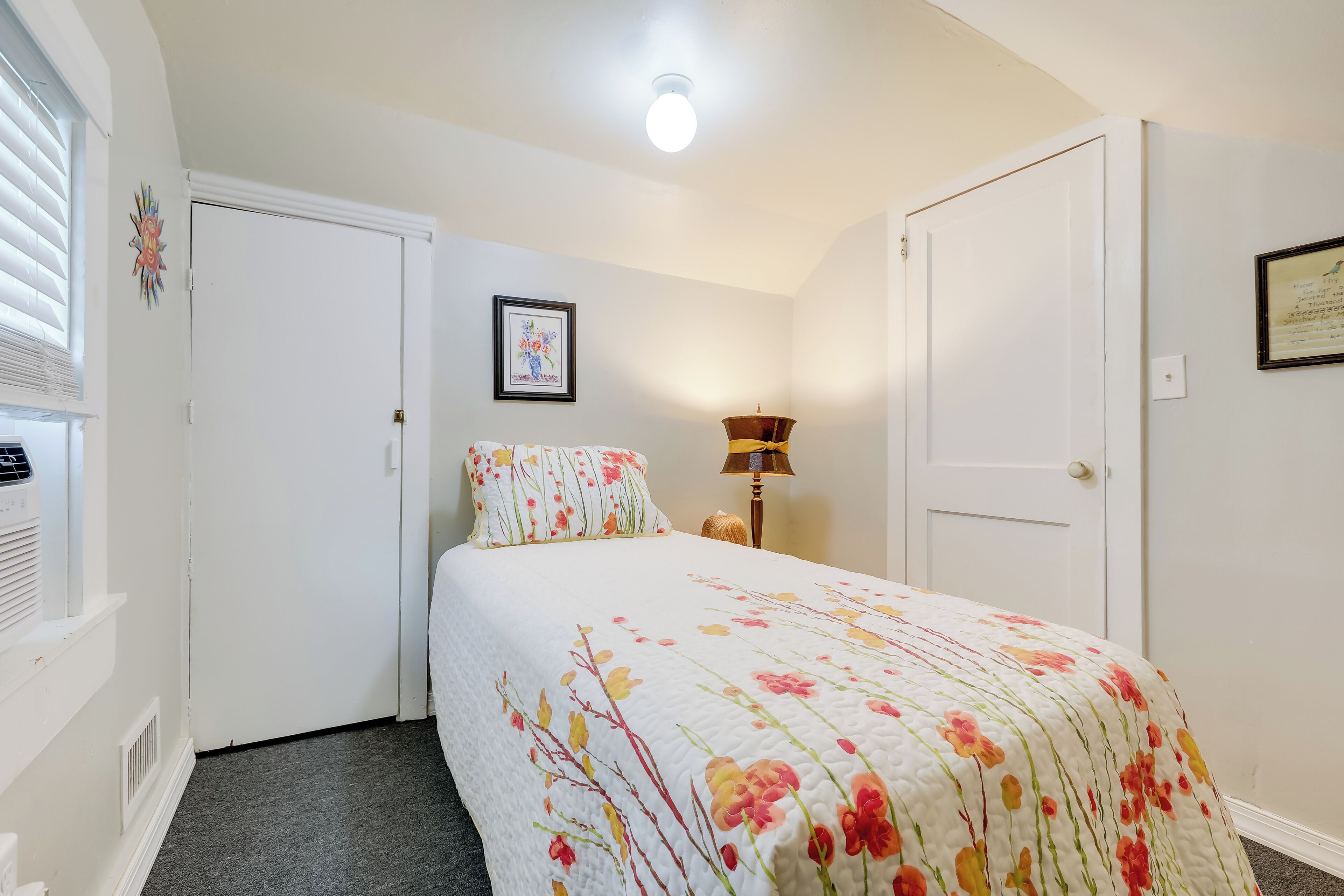 A bedroom with a bed, a nightstand, a lamp, and a door.