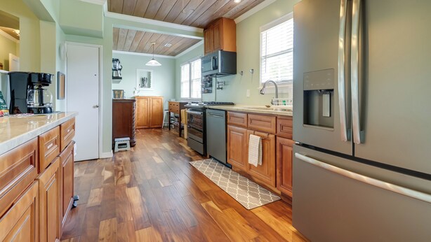 A kitchen with wooden cabinets, a stainless steel refrigerator, a microwave, and a ceiling fan. - Historic Sunrise House w/ Game Room: Near Beach! (Fort Pierce)