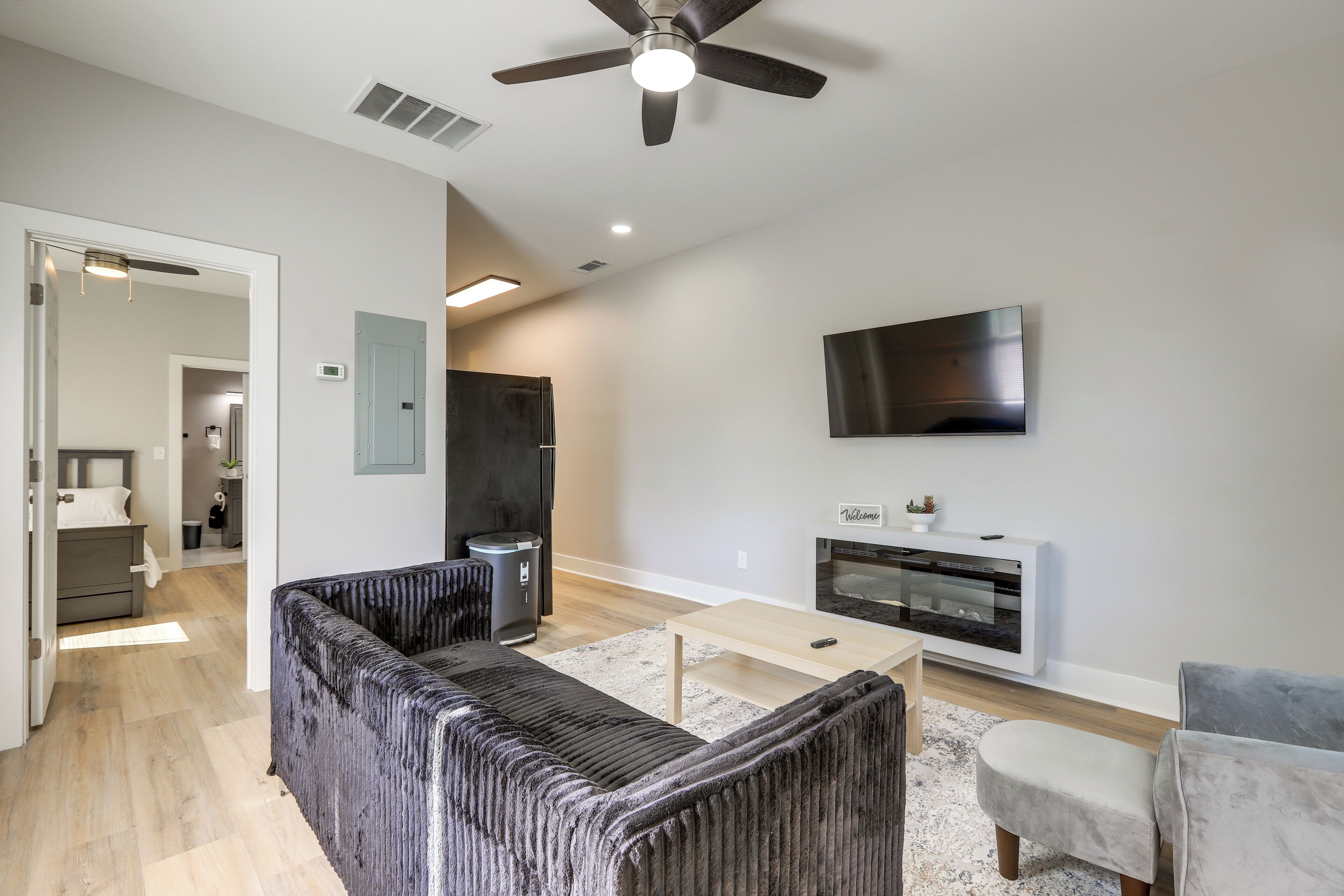 Un salon moderne avec un canapé, une table basse, un téléviseur fixé au mur et un ventilateur de plafond.
