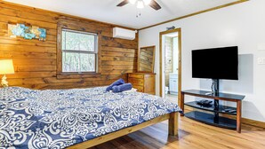 A bedroom with a wooden bed, a television on a stand, and a window with blinds. - Hot Tub & Covered Deck! Long Pond Log Cabin (Long Pond)