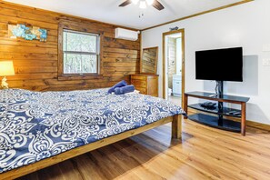A bedroom with a wooden bed, a television on a stand, and a window with blinds.