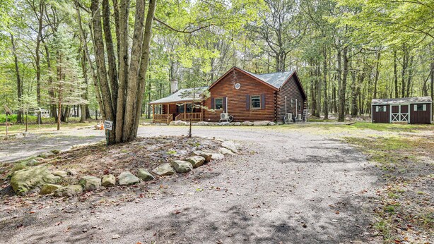 Ein rustikales Holzhaus mit Veranda, umgeben von einem Wald.