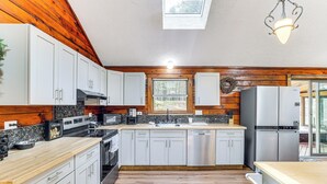 Une cuisine moderne avec un lambris en bois, des appareils électroménagers en acier inoxydable et une lucarne.