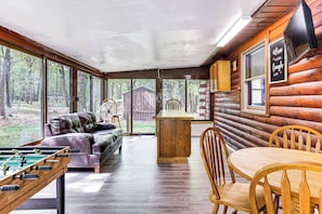 L’intérieur d’un chalet confortable, avec une table de baby-foot, un canapé en cuir et une table à manger entourée de chaises.
