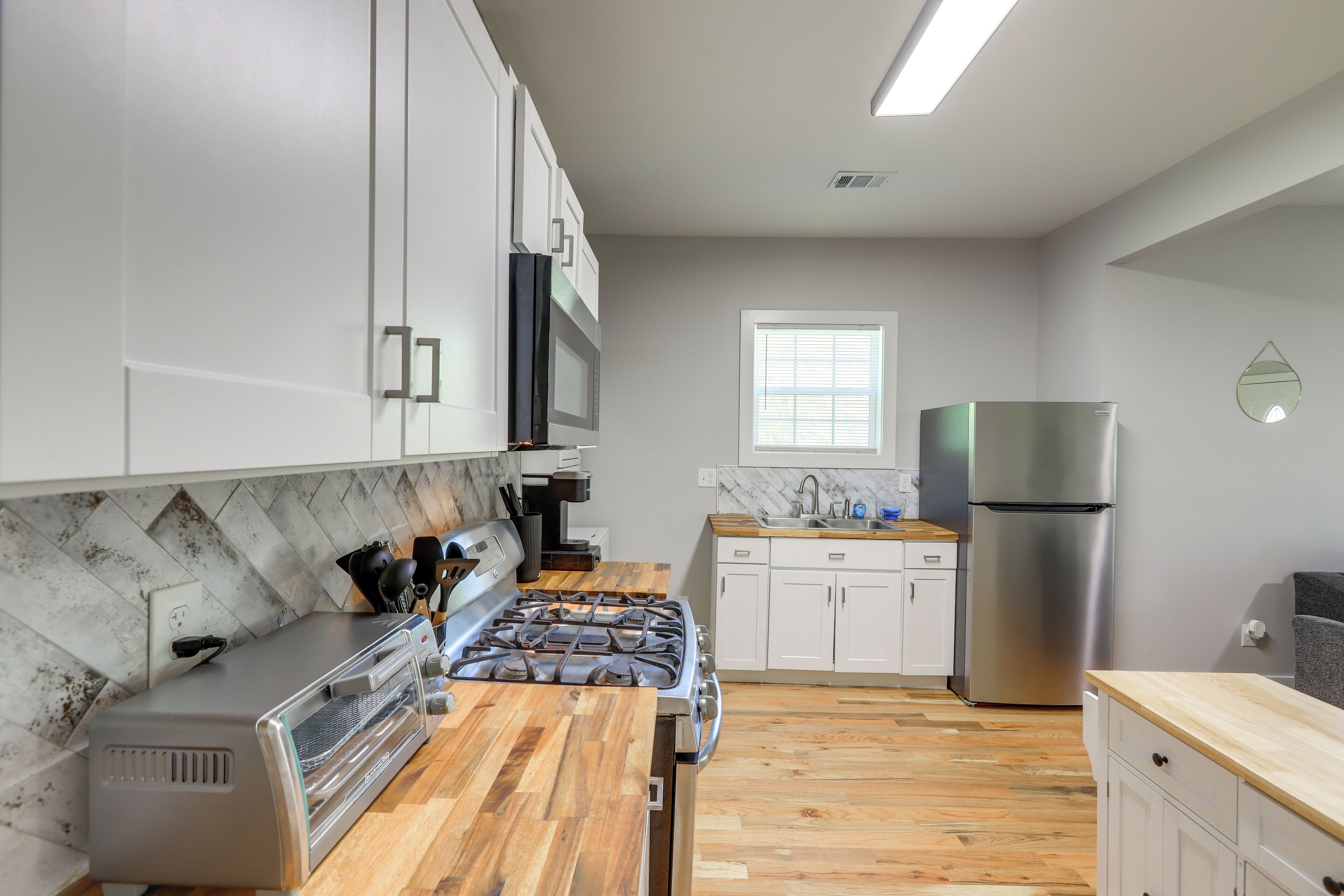 Una cocina moderna con estufa a gas, microondas, refrigerador de acero inoxidable y encimeras de madera.