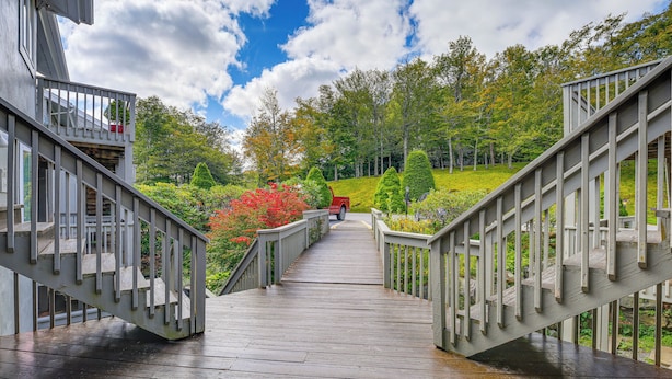 A wooden bridge with railings leading to a red vehicle parked on a grassy hill. - Families Welcome! Sugar Mtn Gem: Golf, Hike & Ski (Banner Elk)