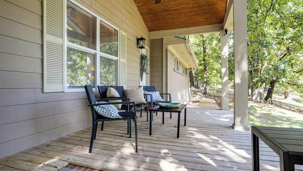 A covered porch with wooden flooring, two chairs with cushions, and a table. - < 1 Mi to Ole Miss & The Grove! Charming Getaway (Oxford)