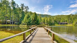 A wooden pier leading to a lake surrounded by trees and a cabin.