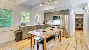 A modern kitchen with wooden flooring, stainless steel appliances, and a dining area with a bench.