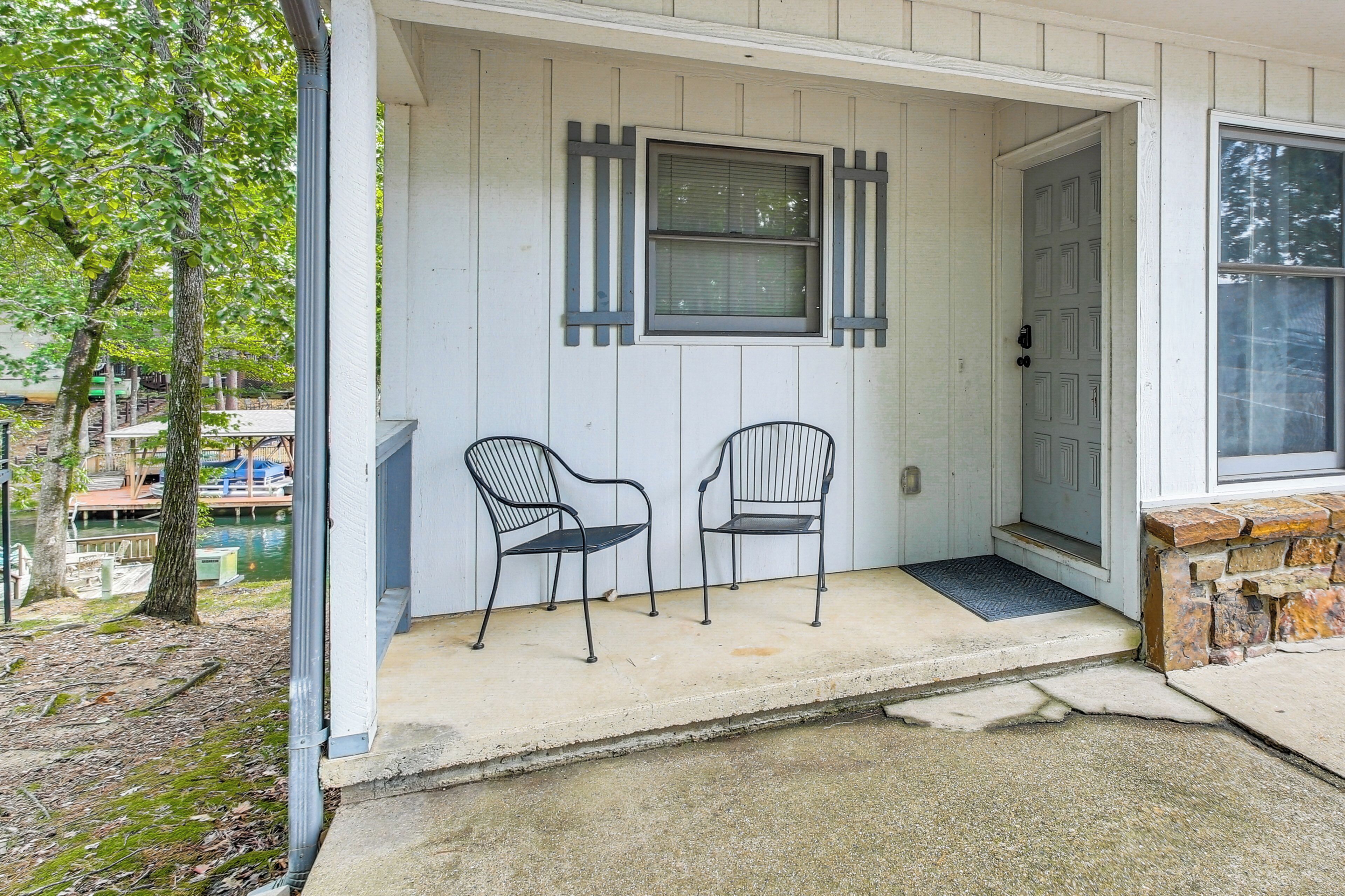 A porch with two metal chairs, a door, and a window with shutters.