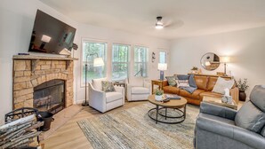 A living room with a stone fireplace, a leather sofa, and a coffee table. - Lake Access, Pools & More: Family Home in Stanwood (Stanwood)